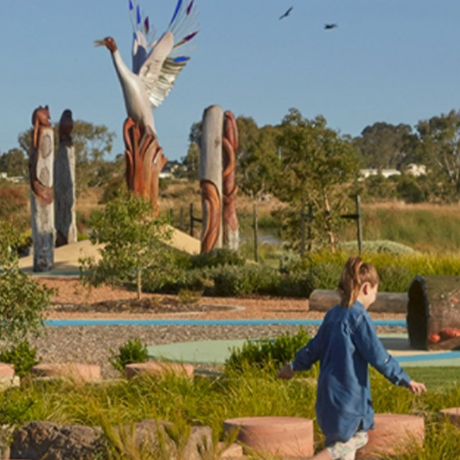 Herpley Estate Park with large bird sculptures in the distance and child playing hopscotch